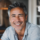Homme souriant aux cheveux gris, chemise bleue.
